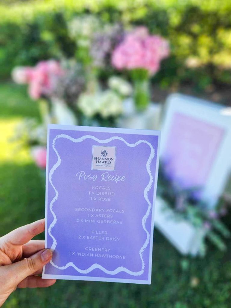 A hand holding a purple card which has a posy recipe printed on it