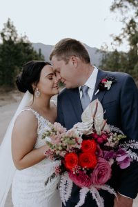 A bride and groom with a wedding bouquet with brightly coloured flowers