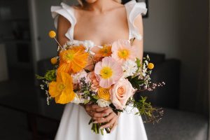 Bride holding a wedding flower bouquet with seasonal poppies