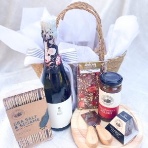 The image shows a bottle of wine, a cheeseboard and knife set, and gourmet treats outside the basket, perfect for any occasion.