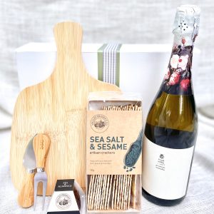 The image shows a gift hamper with a bottle of wine, a cheeseboard, and a knife set, perfect for any occasion.